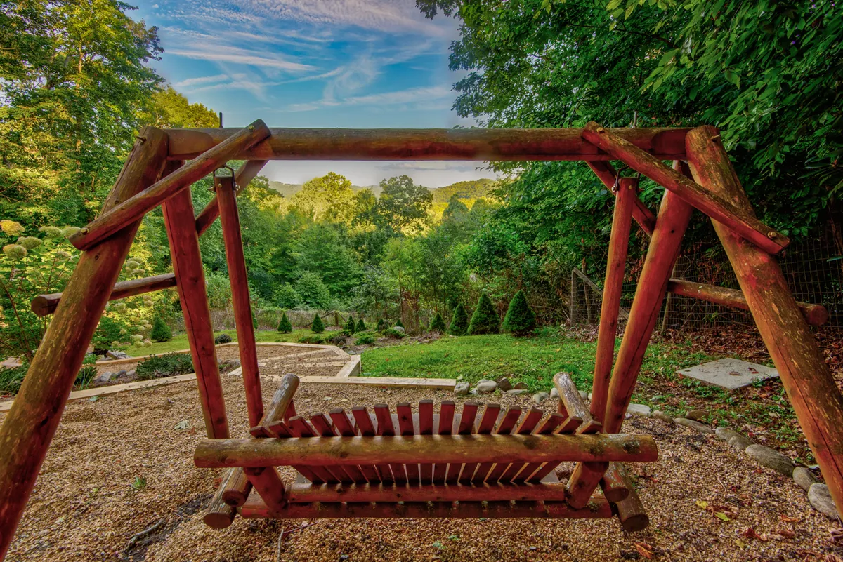 A charming wooden swing set among lush greenery with distant hills in the background. The swing is a clear nod to simple, classic family entertainment, while the surrounding landscape creates a sense of adventure and outdoor exploration.