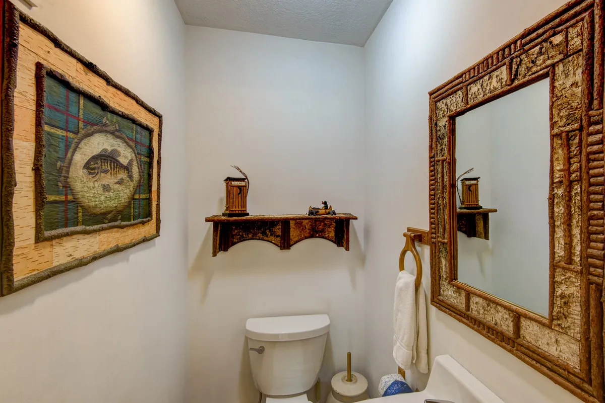A tastefully decorated half bath with rustic wall art, a wooden shelf, and a framed mirror. The space is compact but charming, offering a moment of tranquility and practical convenience for guests.