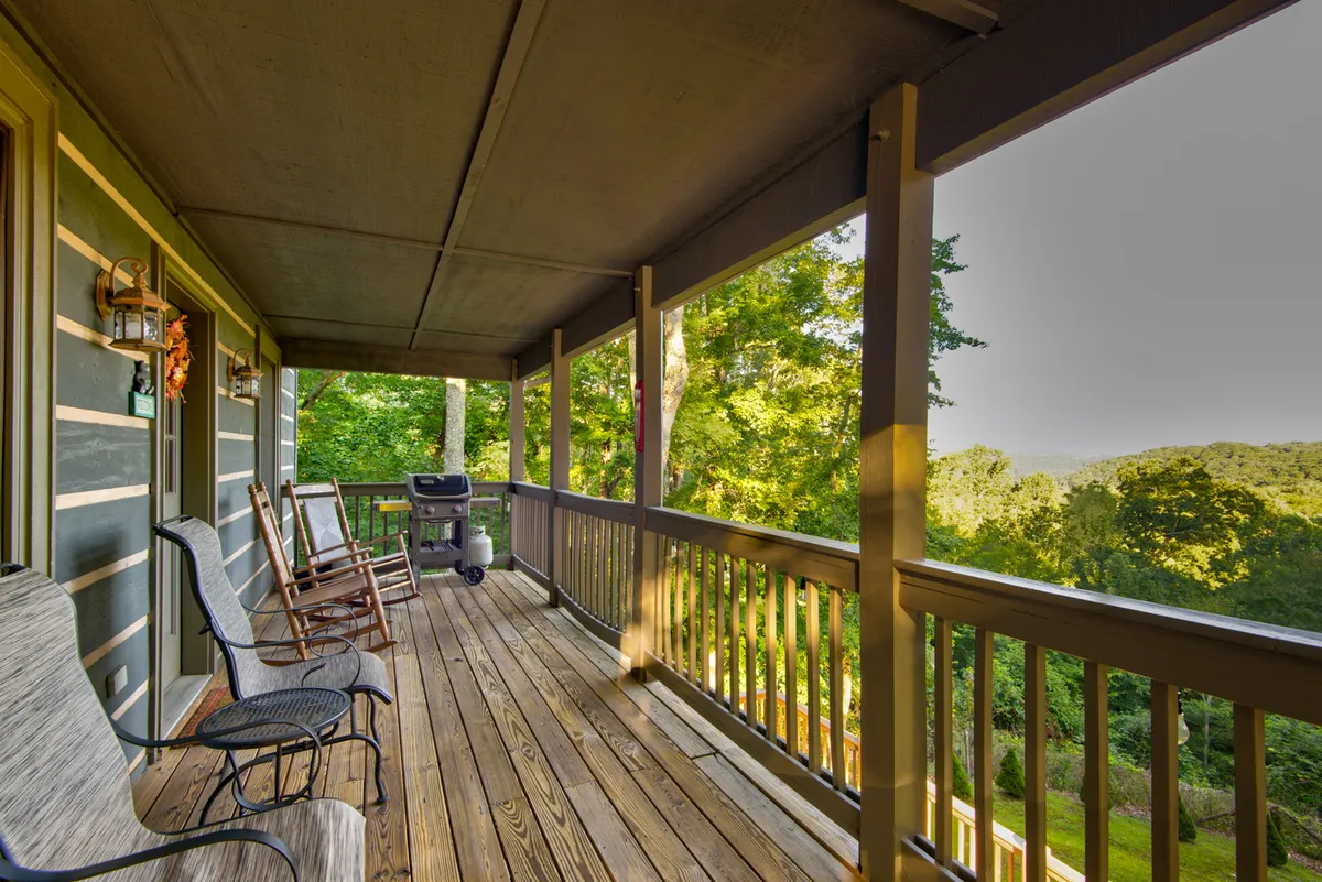 This image features a classic mountain deck with Cracker Barrel-style rocking chairs, a gas grill, and sweeping views of the mountains. The deck is set up for both relaxation and entertaining, making it perfect for morning coffees or sunset barbecues. The natural wood tones and mountain backdrop evoke the High Country lifestyle.