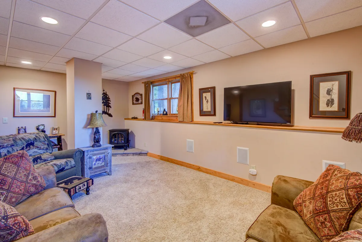 This image features a sofa with decorative pillows facing a television, framed artwork on the wall, and a window with inviting curtains. The setup feels homely and perfect for relaxation, movie-watching, or casual group activities.