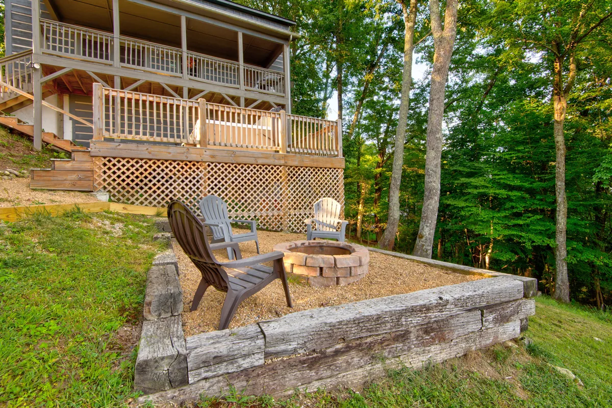 This image focuses on the inviting fire pit area with Adirondack chairs on a wooden deck, set against a lush, green backdrop. It’s the perfect setting for evening gatherings, making s’mores, and sharing mountain stories under the stars.